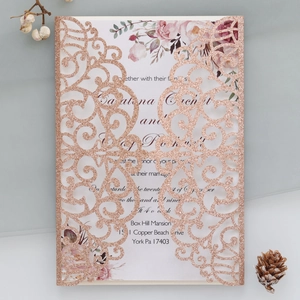 Macro view of rose gold glitter laser cut wedding invitation with floral printed inner card