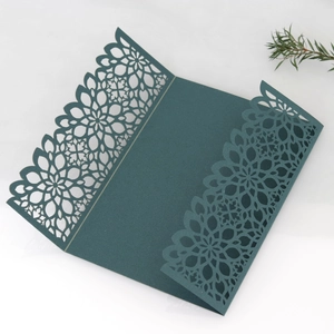 Detail of dark green laser-cut wedding invitation cover with intricate floral patterns