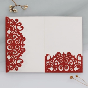Dettaglio dell'invito di nozze laser cut con glitter rossi e motivi floreali europei