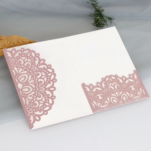 Detailed laser-cut rose gold glitter wedding invitation card on white cardstock