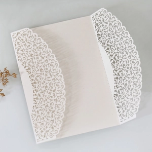 Close-up of laser cut white wedding invitation cover with intricate floral patterns