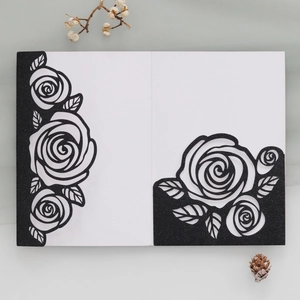 Macro detail of laser-cut rose patterns on elegant black glitter paper invitation card