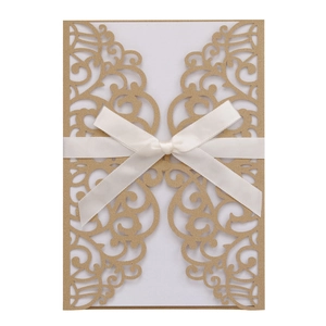 Macro shot of laser-cut gold wedding invitation cover with a white satin bow detail