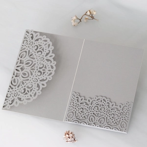 Detailed laser-cut mandala lace pattern on silver-grey invitation with shimmering texture