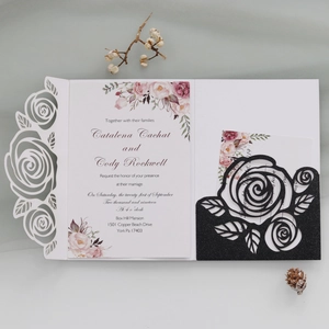 Detailed laser-cut rose wedding invitation with pink floral insert and black glitter pocket