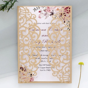 Close-up of laser-cut gold wedding invitation with watercolor floral pattern