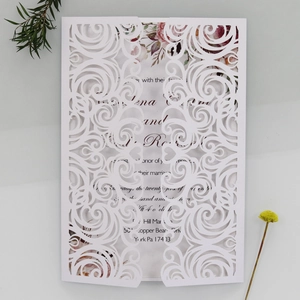 Detail of white laser-cut wedding invitation with intricate spiral hollow patterns