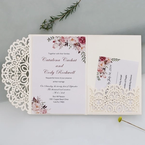 Detail of laser-cut wedding invitation with cream hollow pattern and pink floral inserts