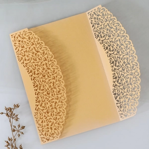 Close-up of laser-cut wedding invitation featuring intricate golden floral patterns