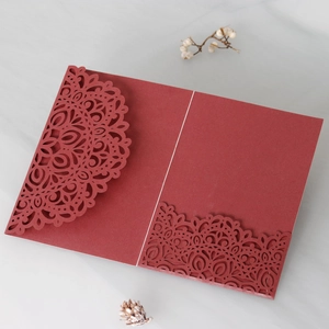 Detail of burgundy laser-cut invitation card with intricate lace mandala patterns