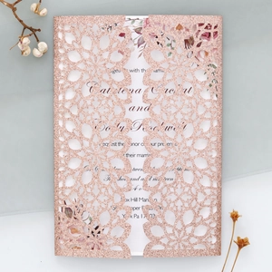 Macro detail of laser cut glitter paper wedding invitation with rose gold floral texture