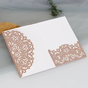 Detail of rose gold laser cut glitter wedding invitation with mandala hollow pattern