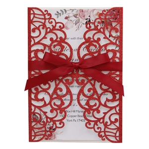 Glittery red laser-cut wedding invitation with elegant satin bow and floral inner card