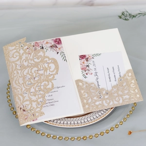 Detail of laser-cut gold glitter wedding invitation with floral insert and RSVP card