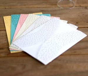 Detailed laser-cut floral lace wedding invitations in a colorful pearlescent paper set