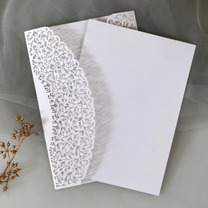 Close-up of white laser-cut pearlescent paper wedding invitation with floral pattern
