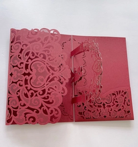 Detailed laser-cut hollow lace design with cupid and floral arch on red wedding invitation