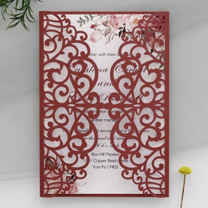 Detailed laser-cut vine patterns on dark red wedding invitation cover with floral inner card