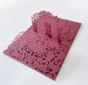 Macro detail of laser-cut 3D wedding card with kissing couple silhouette and heart arch