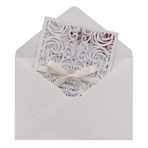 Detail of laser-cut butterfly wedding invitation with white scrollwork and silk ribbon bow
