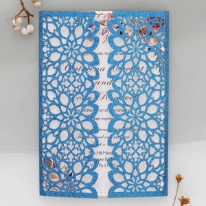 Macro view of blue glitter laser-cut invitation with intricate floral mandala patterns