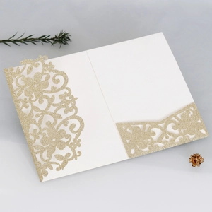Dettaglio dell'invito di nozze dorato glitterato con intricati motivi floreali tagliati al laser