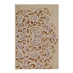 Macro detail of laser-cut hollow floral pattern on warm beige wedding invitation card