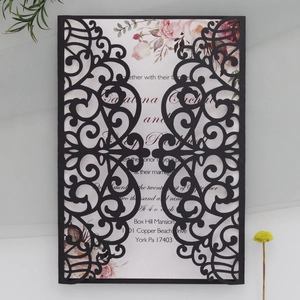 Macro detail of laser-cut hollow scrollwork on elegant dark wedding invitation cover