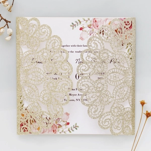 Close-up of laser-cut gold glitter wedding invitation with floral printed inner card