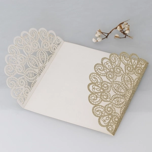 Macro detail of laser-cut wedding invitation with cream hollow lace and gold glitter