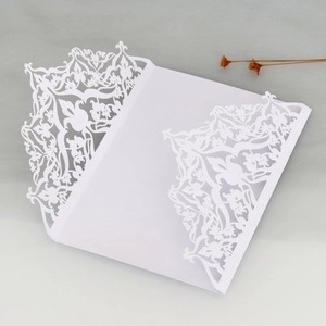 Detail of laser-cut floral pattern and intricate lace design on a white wedding invitation
