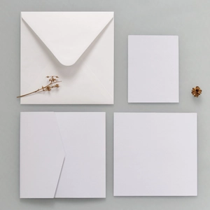 Flat lay of minimalist white invitation cards and envelopes with dry plant stems