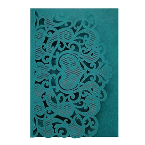 Intricate laser-cut heart pattern on dark teal wedding invitation card with vintage motifs
