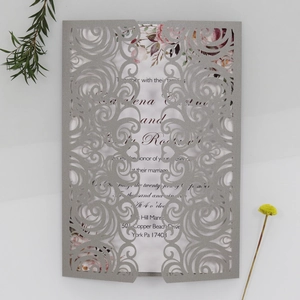 Detailed laser-cut scrollwork on silver grey wedding invitation with pink floral inner card