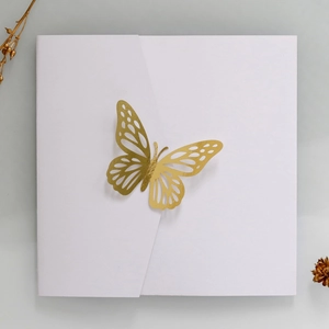 Macro detail of square wedding invitation with 3D golden hollow butterfly cutout