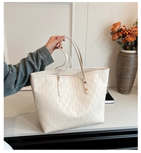 Detail of beige quilted tote bag with refined diamond stitching and golden rivets