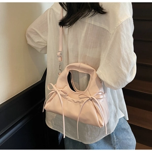Détail du sac à main plissé rose avec nœuds et bandoulière réglable sur un mannequin