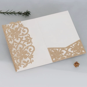 Dettaglio dell'invito di nozze tagliato al laser con glitter dorati e fiori eleganti