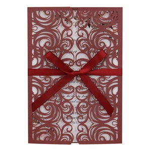 Close-up of laser cut burgundy wedding invitation with elegant satin bow detail