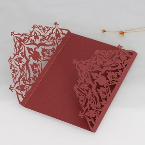 Detailed laser-cut pattern on burgundy cardstock for wedding invitation covers