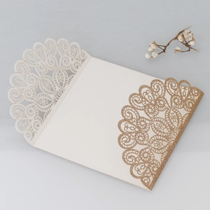 Detailed laser-cut lace wedding invitation featuring gold glitter and elegant hollow design