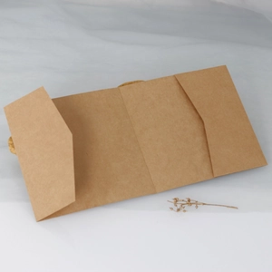 Close-up of tri-fold kraft paper invitation cover with natural fiber texture and dried flowers