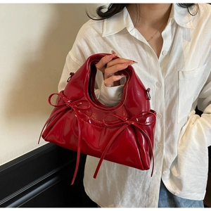 Détail d'un sac à main en cuir verni rouge vif avec des nœuds décoratifs élégants
