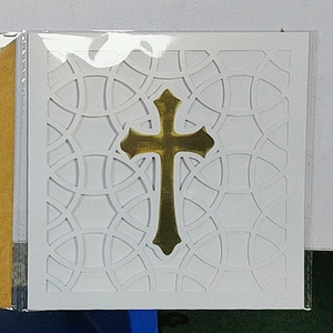 Detail of laser-cut white baptism card with metallic gold cross and intricate hollow patterns