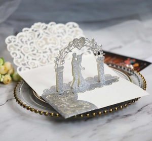 Detail of 3D laser cut wedding card with silver glitter finish and kissing couple scene