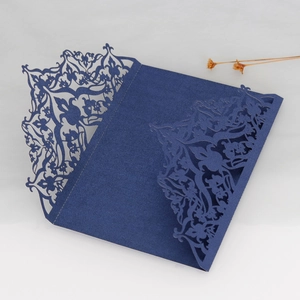 Detail showing laser-cut navy blue wedding invitation cover with elegant floral patterns