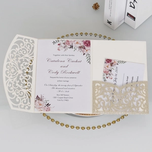Détail d'invitation de mariage découpée au laser avec pochette dorée et motif floral