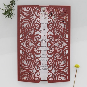 Detail of burgundy laser-cut wedding invitation with elegant floral insert on white lace