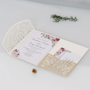 Détail d'invitation de mariage découpée au laser avec pochette dorée et fleurs