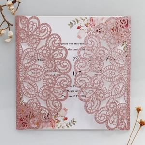 Detail of pink glitter laser-cut wedding invitation with intricate lace peacock patterns